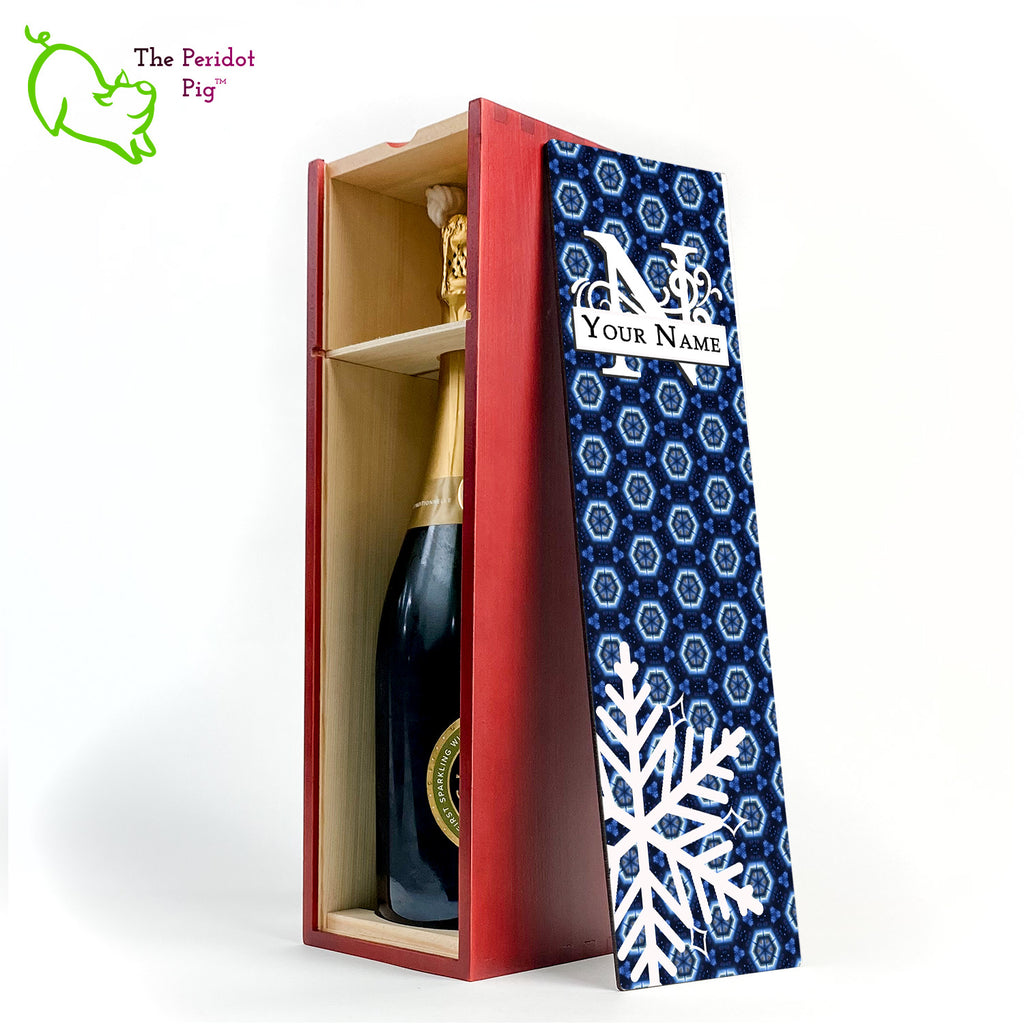 The wine box front panel is decorated in a glossy, detailed print with a white monogram and space for a customized name. This model has a deep blue background with crystalized pattern. In the foreground is a large white snowflake. Shown in cherry with an interior view of a sample wine bottle.