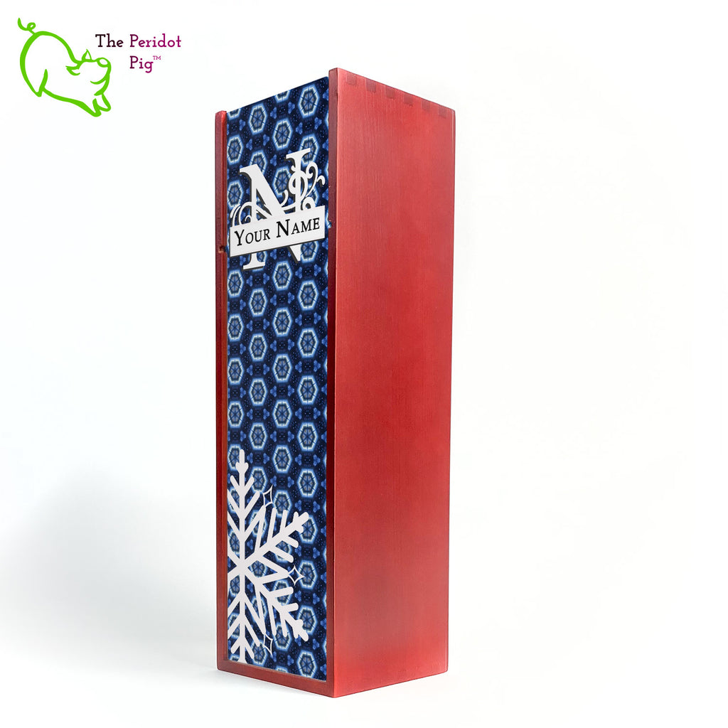 The wine box front panel is decorated in a glossy, detailed print with a white monogram and space for a customized name. This model has a deep blue background with crystalized pattern. In the foreground is a large white snowflake. Shown in cherry front view.