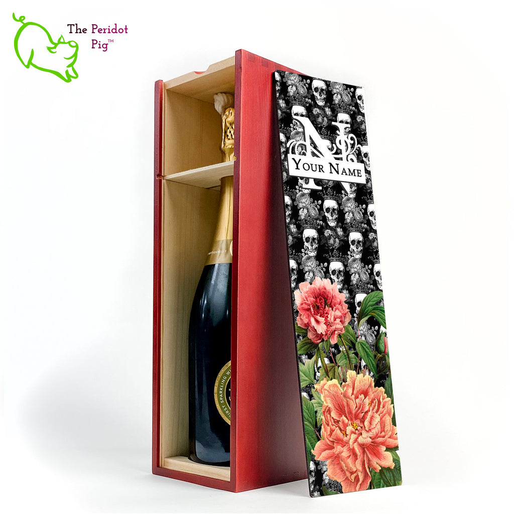 The front panel is decorated in a glossy, detailed print with a monogram and space for a customized name. This model has a background of Victorian skulls wearing a crown. in the foreground, there are two colorful peonies with green foliage. Front view in cherry showing the interior of the box and sample bottle of wine.