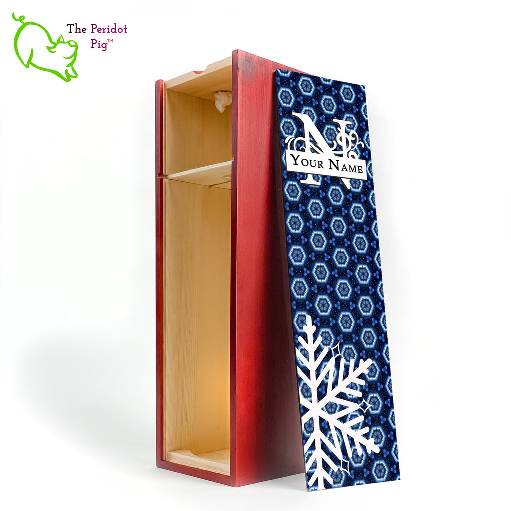 The wine box front panel is decorated in a glossy, detailed print with a white monogram and space for a customized name. This model has a deep blue background with crystalized pattern. In the foreground is a large white snowflake. Shown in cherry with an interior view.
