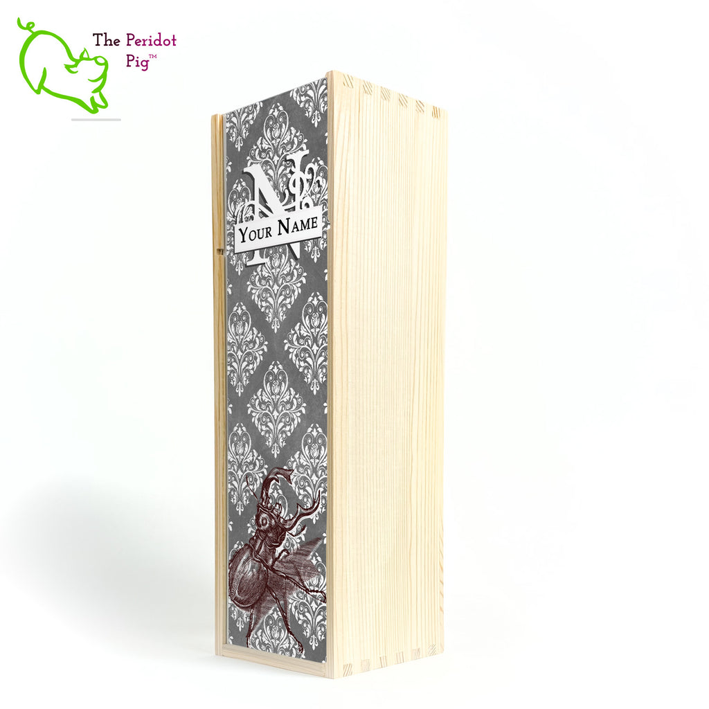 The wine box front panel is decorated in a glossy, detailed print with a white monogram and space for a customized name. This model has a gray background with white decorative scroll work. In the foreground is a large burgundy line drawing of a rhinoceros beetle. Natural version front view.