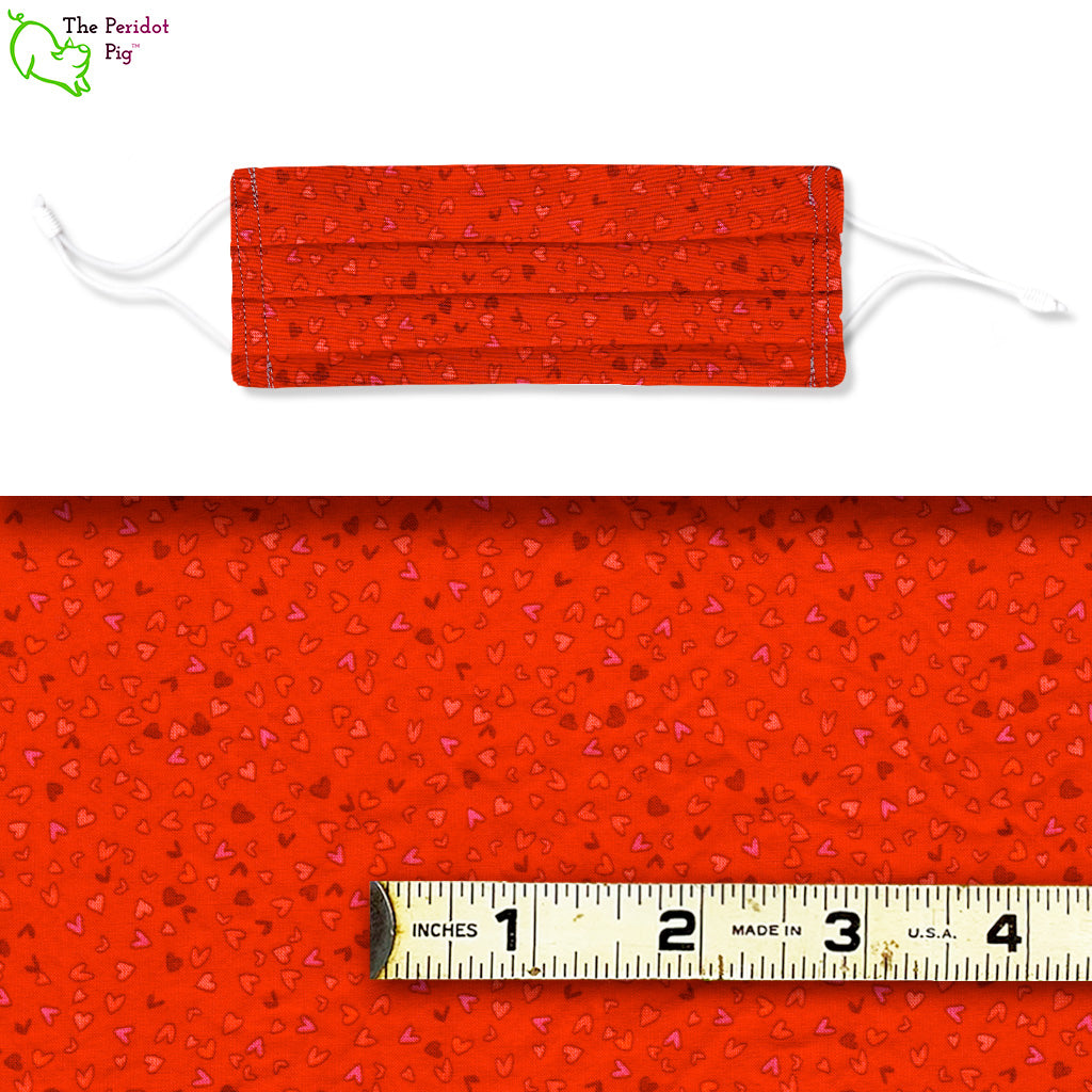 Show your love with a mask featuring little hearts in red, pink, purple and orange on a red background. Called Bitty Red Hearts. Shown with ruler.