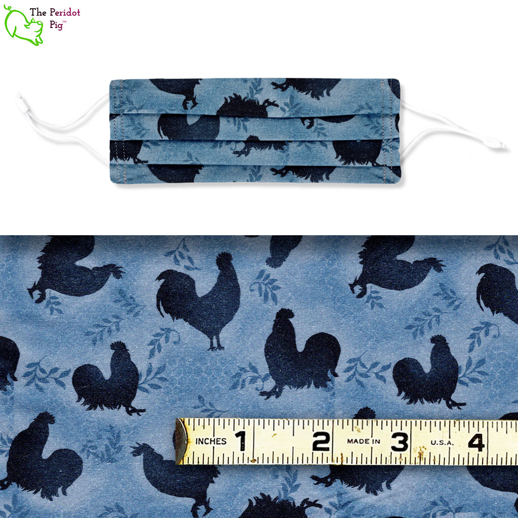 this mask has rooster silhouettes on a dusty blue background. There's a hint of honeycomb amongst the leaves. Shown with ruler.