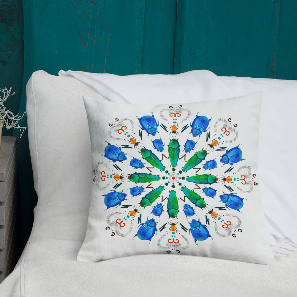 A colorful mandala of beetles graces this white pillow and is availble in either 18"x18" or 22"x22" sizes. The image is printed on both the front and back. The center beetles have shades of bright green.  The smaller beetles are blue and orange. 18" shown on a bed.