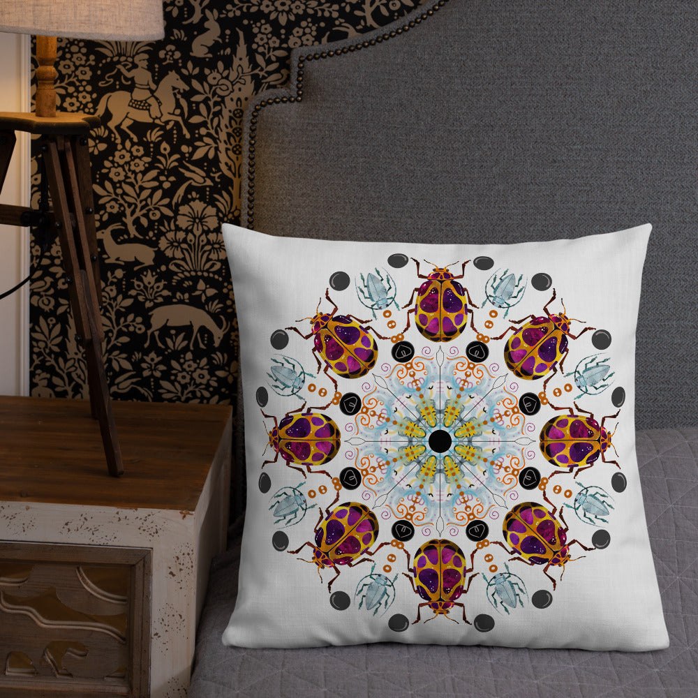 A colorful mandala of beetles graces this white pillow. The larger beetle has shades of violet surrounded by gold. The smaller beetle is in a delicate shade of blue. Printed on a bright, white casing these bugs really pop! Shown in size 22"x22" on a bed.