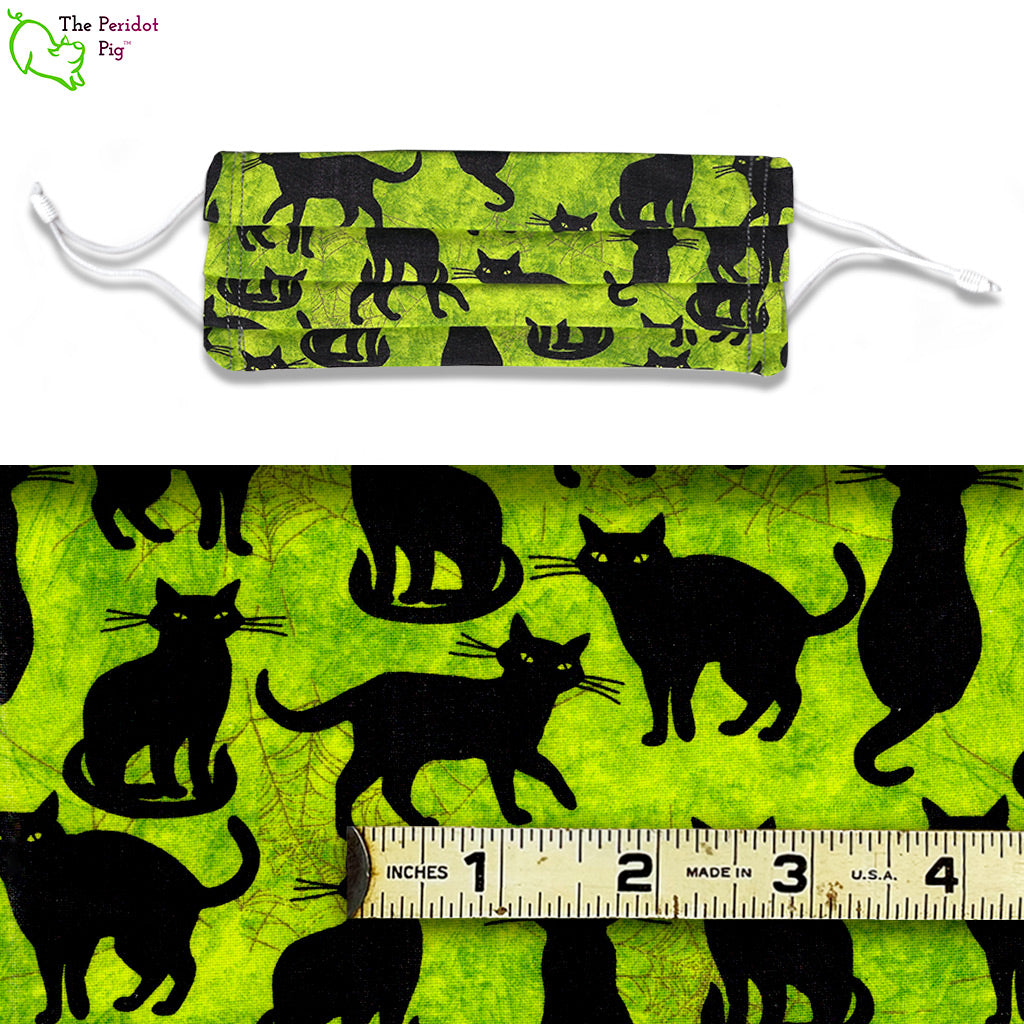 A collection of slinky and stylish black cats set on a bright chartreuse background. with a bit of spider web. Called Black Cats. a view of the mask and fabric scale.