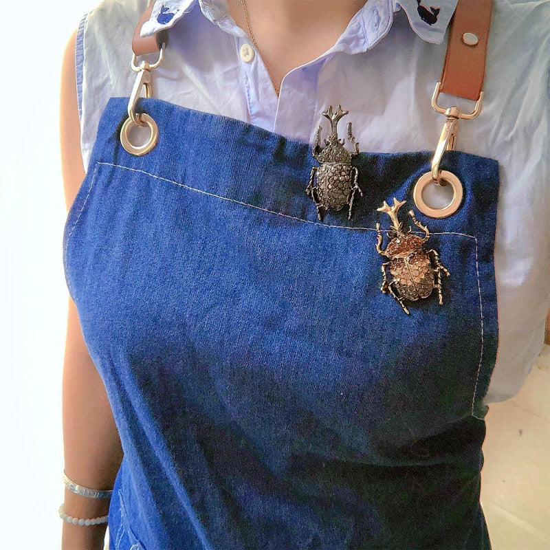 An image showing the two styles of rhino beetle brooches on a woman's lapel.
